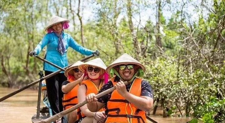 Visitors in orange life jackets rowing a boat through a mangrove canal on a 6-day Vietnam tour package in the south, Mekong Delta, Vietnam